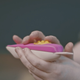A woman touching a tactile pregnancy test with raised bumps to indicate a positive result.